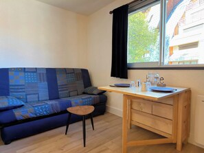 Ein kleines Zimmer mit einer Couch, einem Holztisch und einem Fenster.