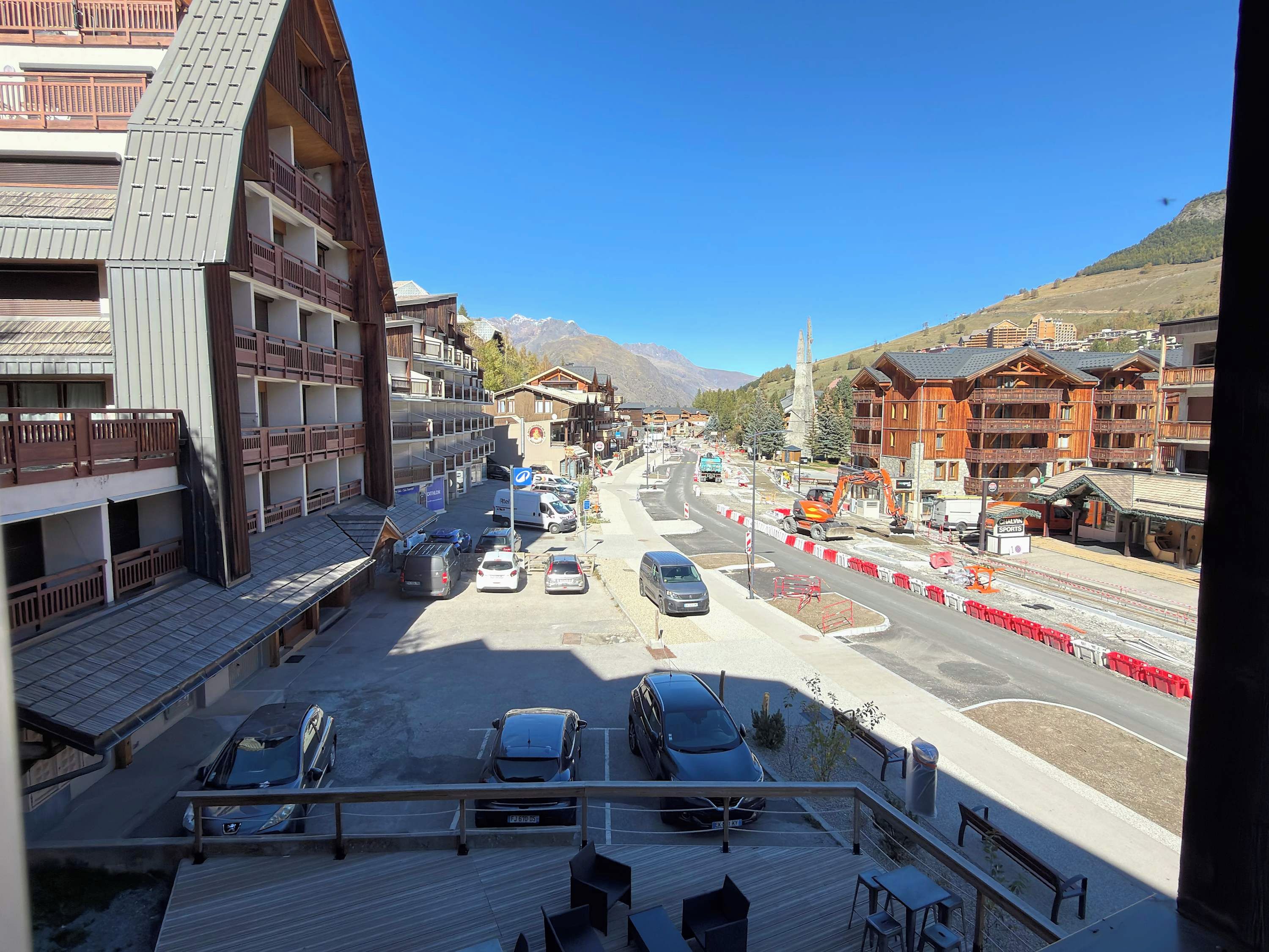Una vista di strada con edifici, auto parcheggiate e cielo sereno.