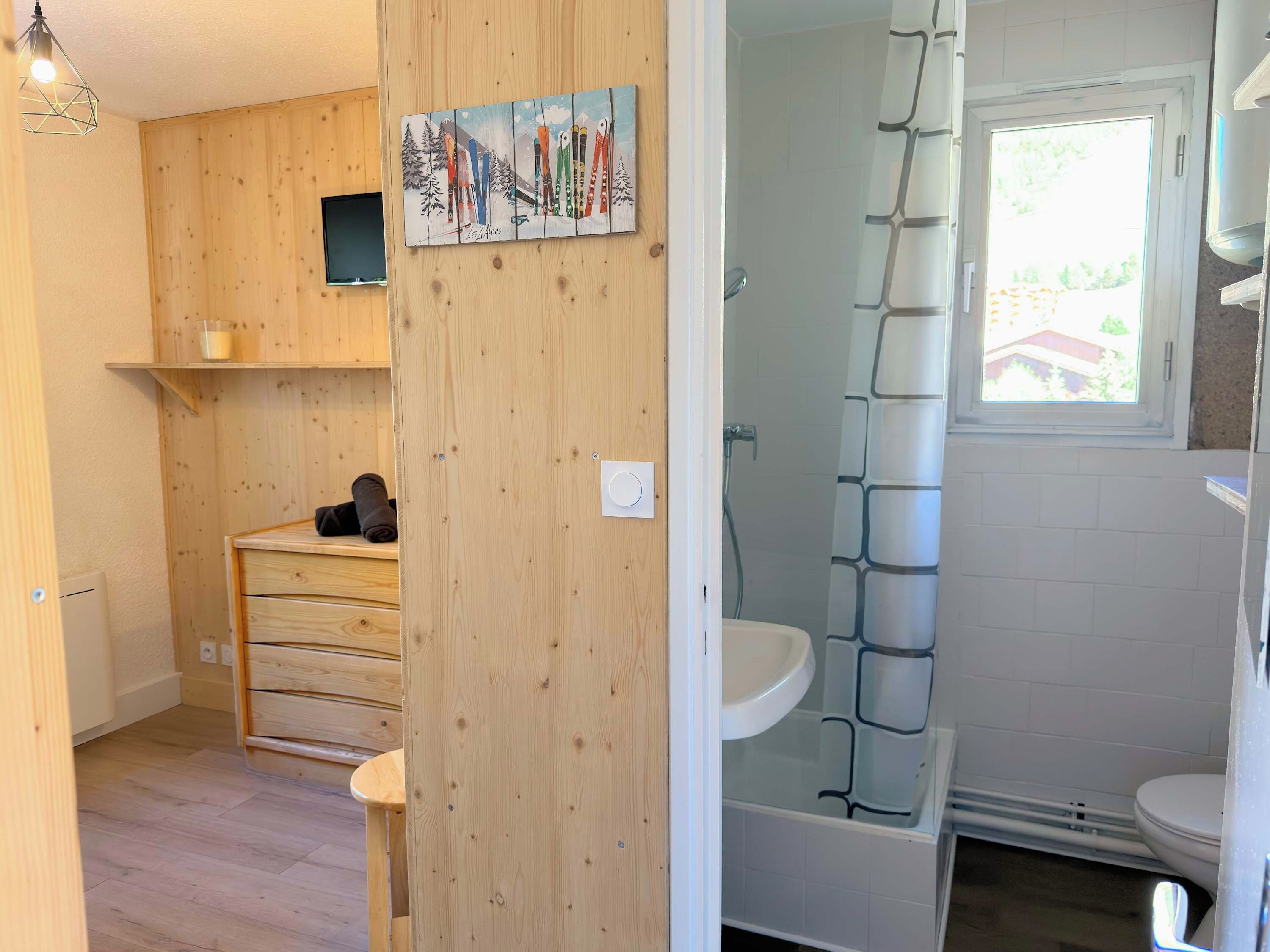 Un intérieur en bois comprenant une douche, un lavabo et une petite étagère avec une serviette.
