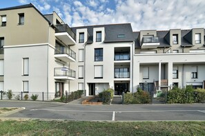 A modern multi-story residential building with balconies, a gated entrance, and a well-maintained lawn. - L'Instant Émeraude - One Bedroom Apartment, Sleeps 2 (Dinard)