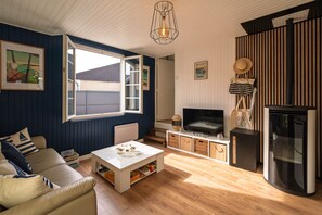 A living room with a sofa, coffee table, TV, and a fireplace. - La Maison entre 2 Caps - 2km de Fréhel (Plurien)