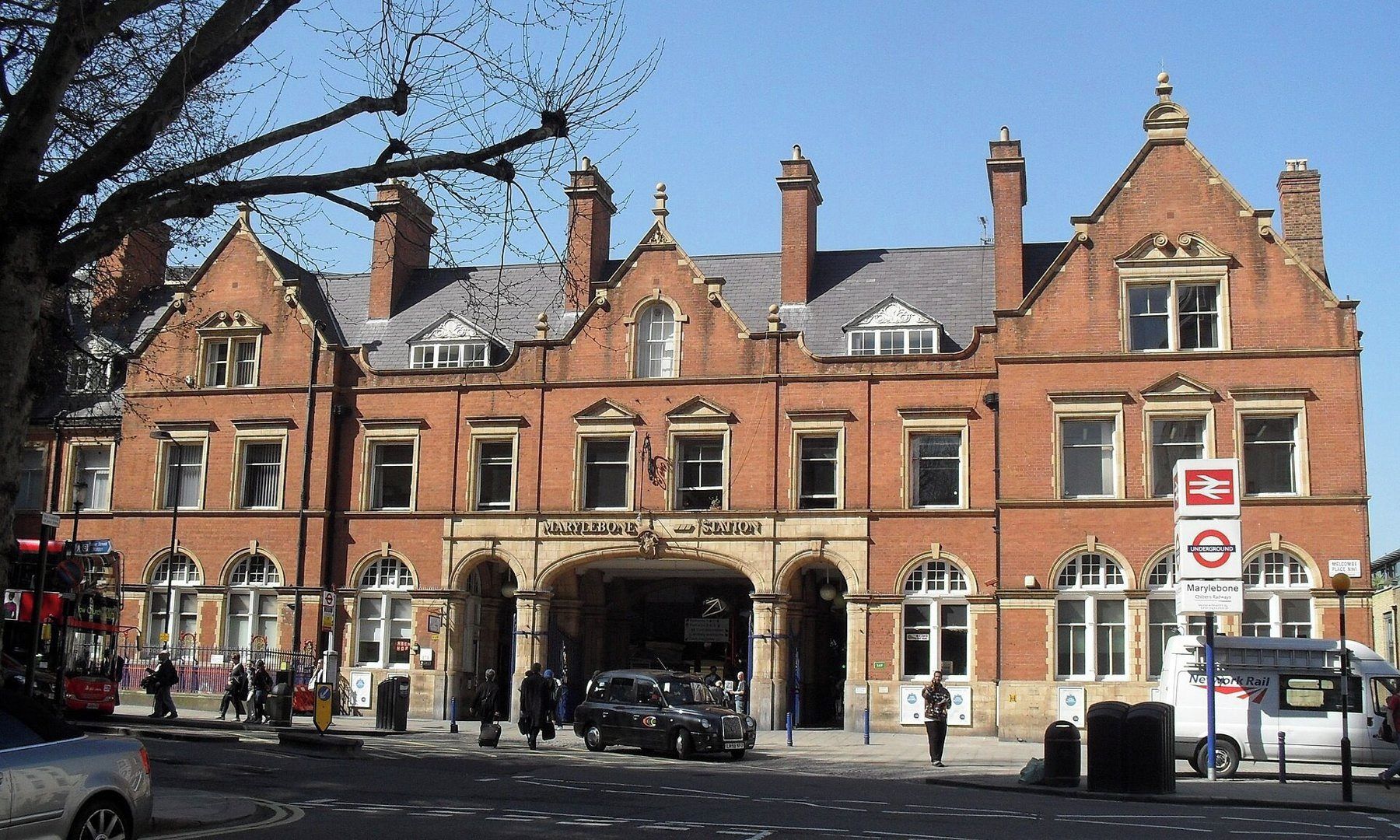Un edificio histórico con una entrada destacada, un cartel de la estación Marylebone Underground y una parada de autobús cerca.