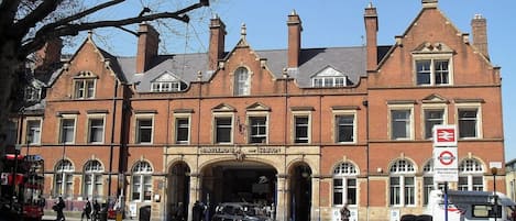 Un edificio histórico con una entrada destacada, un cartel de la estación Marylebone Underground y una parada de autobús cerca.