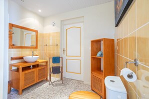 Ein Badezimmer mit einem Holz-Waschtisch, einem Waschbecken, einem Spiegel, einem Handtuchhalter und einer Toilette.