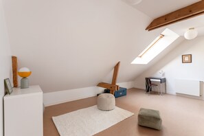 A room with a sloped ceiling, a skylight, a desk, a chair, a lamp, a radiator, and a white rug. - L'Archi - Maison de ville pour 6 (Rennes)