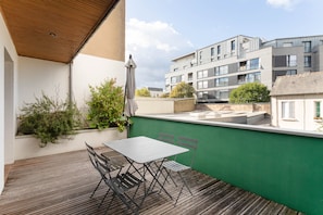 A balcony with a table and chairs, a green wall, and a view of modern buildings. - L'Archi - Maison de ville pour 6 (Rennes)