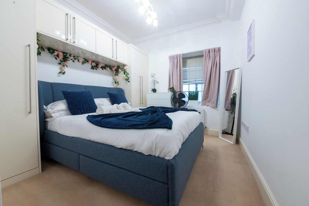 A bedroom with a bed, a dresser, a mirror, and a window with curtains.