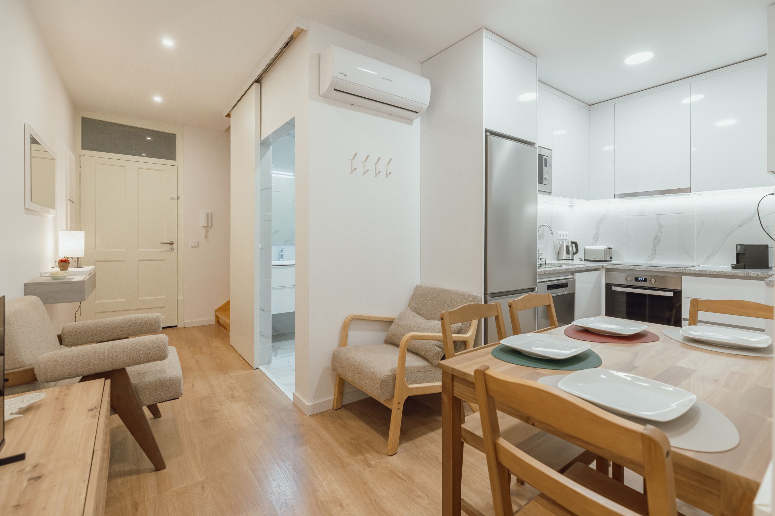 A modern kitchen with white cabinets, a stainless steel refrigerator, and a microwave.