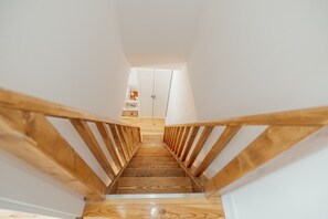 A wooden staircase leading to a room with a white door and a shelf with items. - Typical JOY Duplex by Vacationy (Porto)