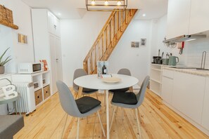 A modern kitchen with a dining area, wooden flooring, white cabinetry, and a staircase. - Typical JOY Duplex by Vacationy (Porto)
