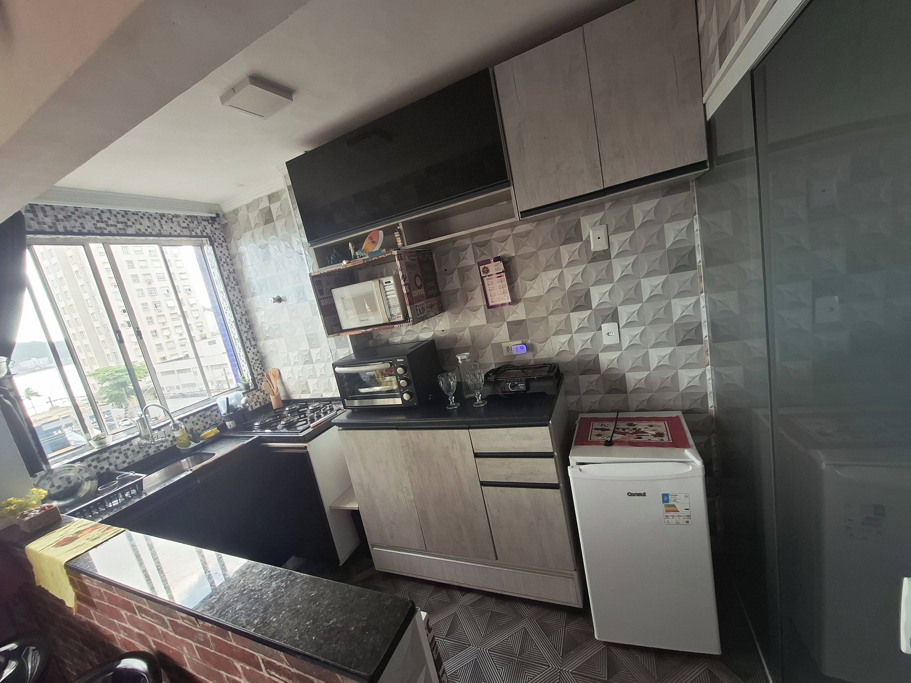 Een moderne keuken met een gasfornuis, een magnetron, een broodrooster en een koelkast.