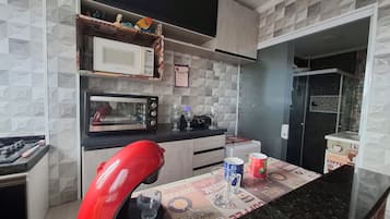 Een keuken met een magnetron, broodrooster en koffieapparaat. Er ligt een tafelonderzetter met koffiethema op het aanrecht.