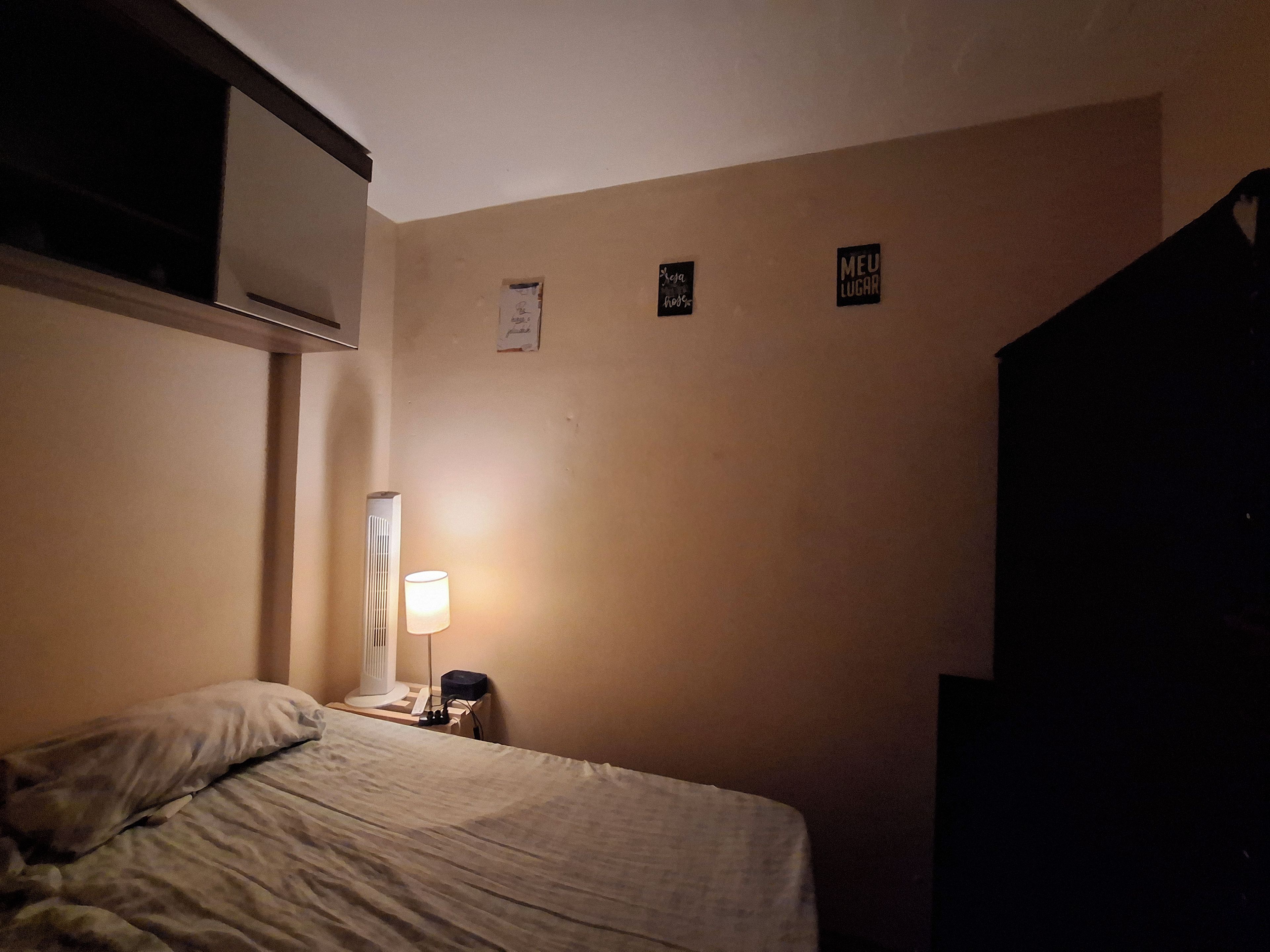 Een hotelkamer met een bed, een bedlamp, een verwarming en een muur met drie bordjes.