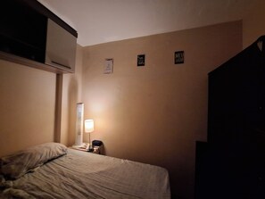 Ein Hotelzimmer mit einem Bett, einer Nachttischlampe, einem Heizkörper und einer Wand mit drei Schildern.