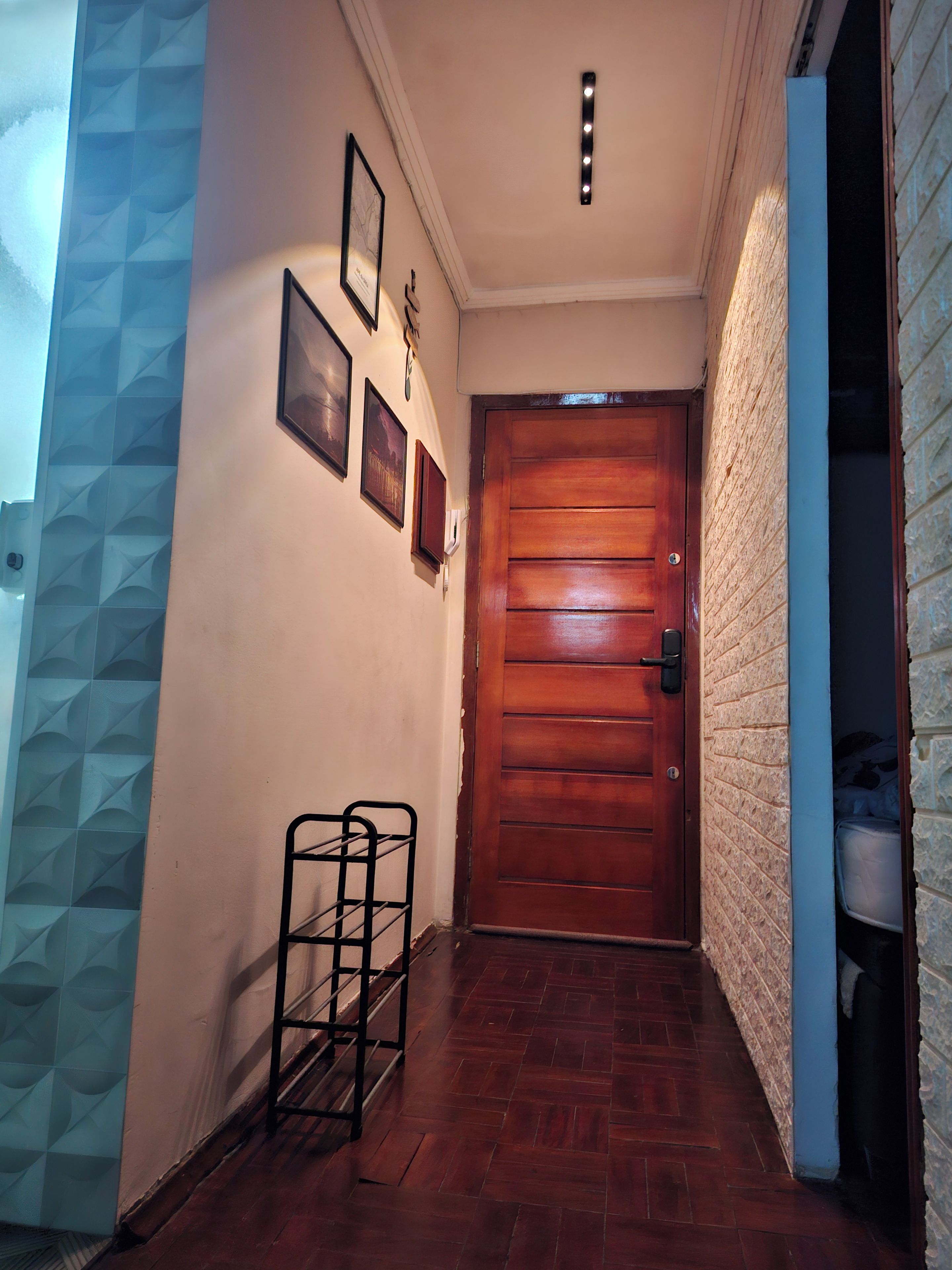 Un couloir avec une porte en bois, un cadre photo fixé au mur et un étagère en métal.