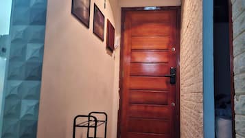 Un couloir avec une porte en bois, un cadre photo fixé au mur et un étagère en métal.