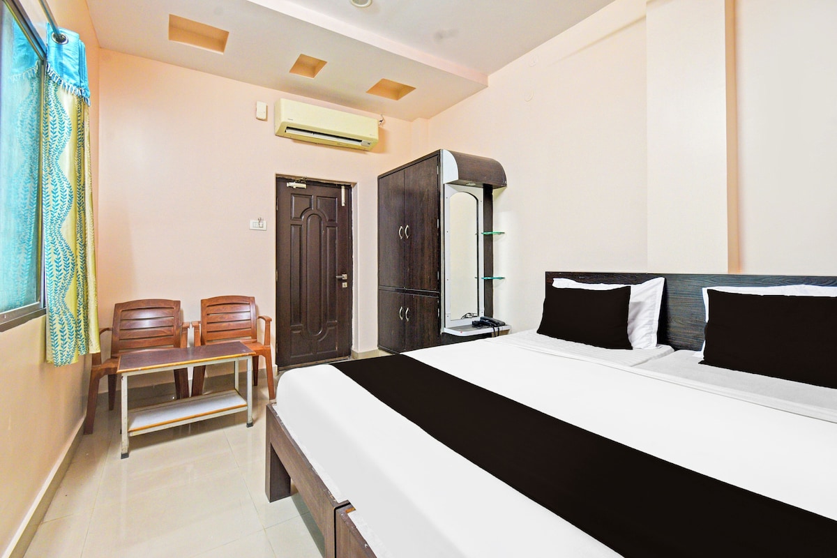 A bedroom with a bed, a desk, a chair, a wardrobe, and an air conditioning unit.