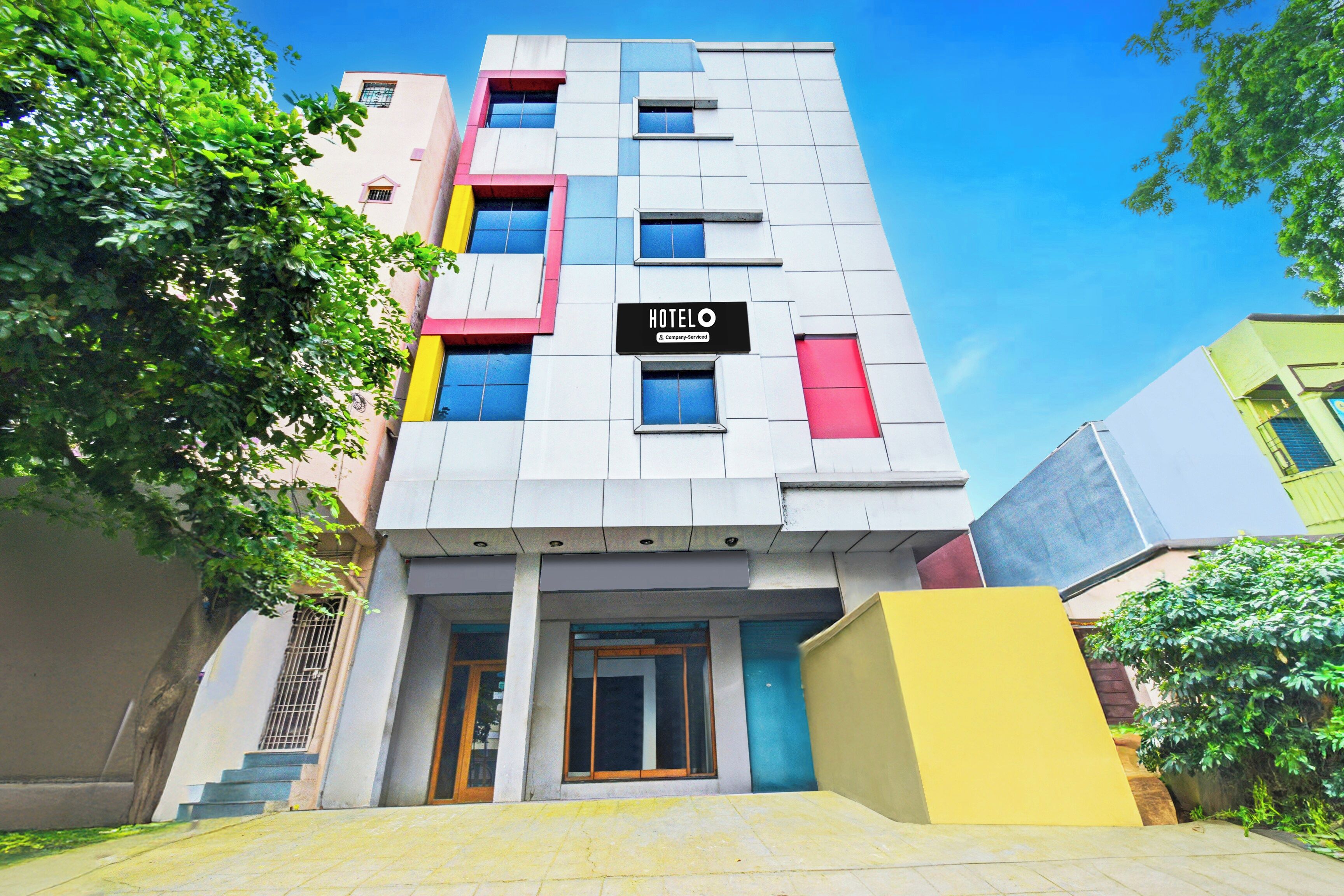 A multi-story hotel with a modern facade, a visible entrance, and a sign indicating it is a company-serviced hotel.