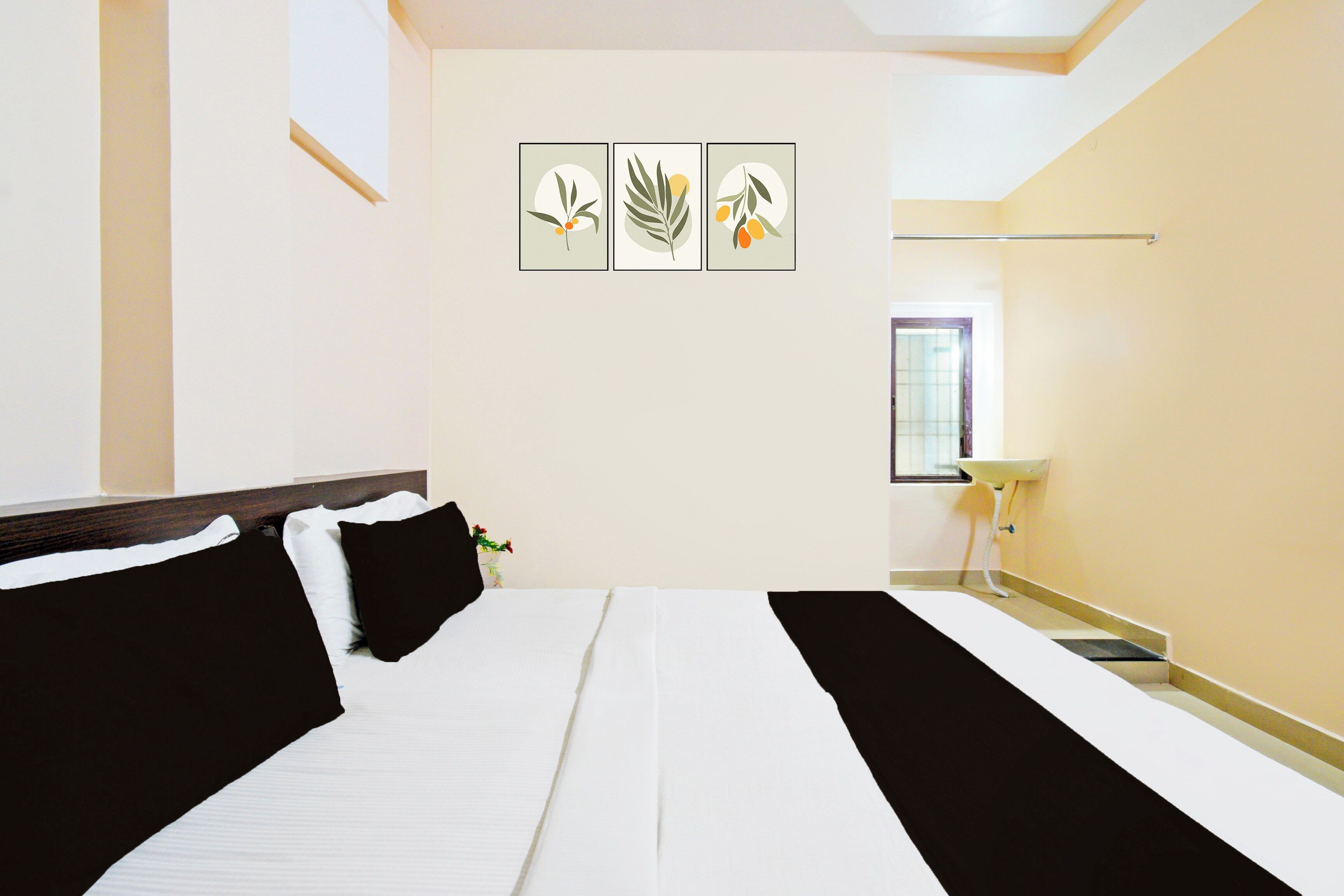 A hotel room with a bed, a bedside table, a window, and wall art.