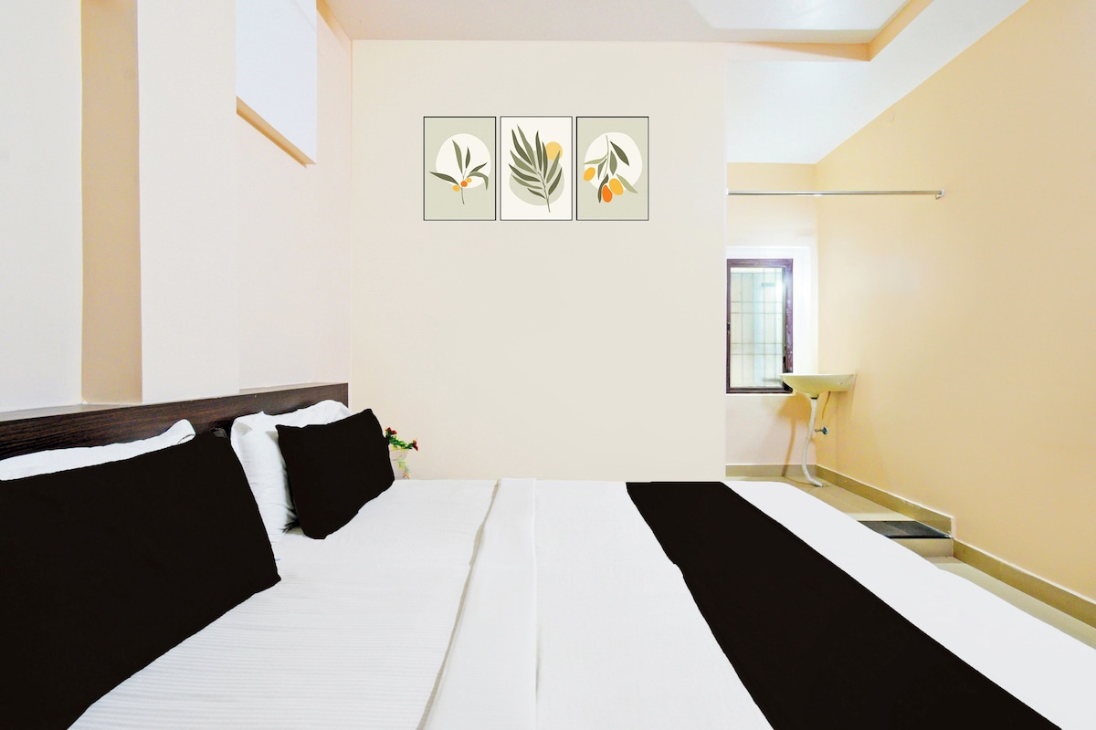 A hotel room with a bed, a bedside table, a window, and wall art.