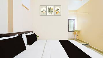 A hotel room with a bed, a bedside table, a window, and wall art.