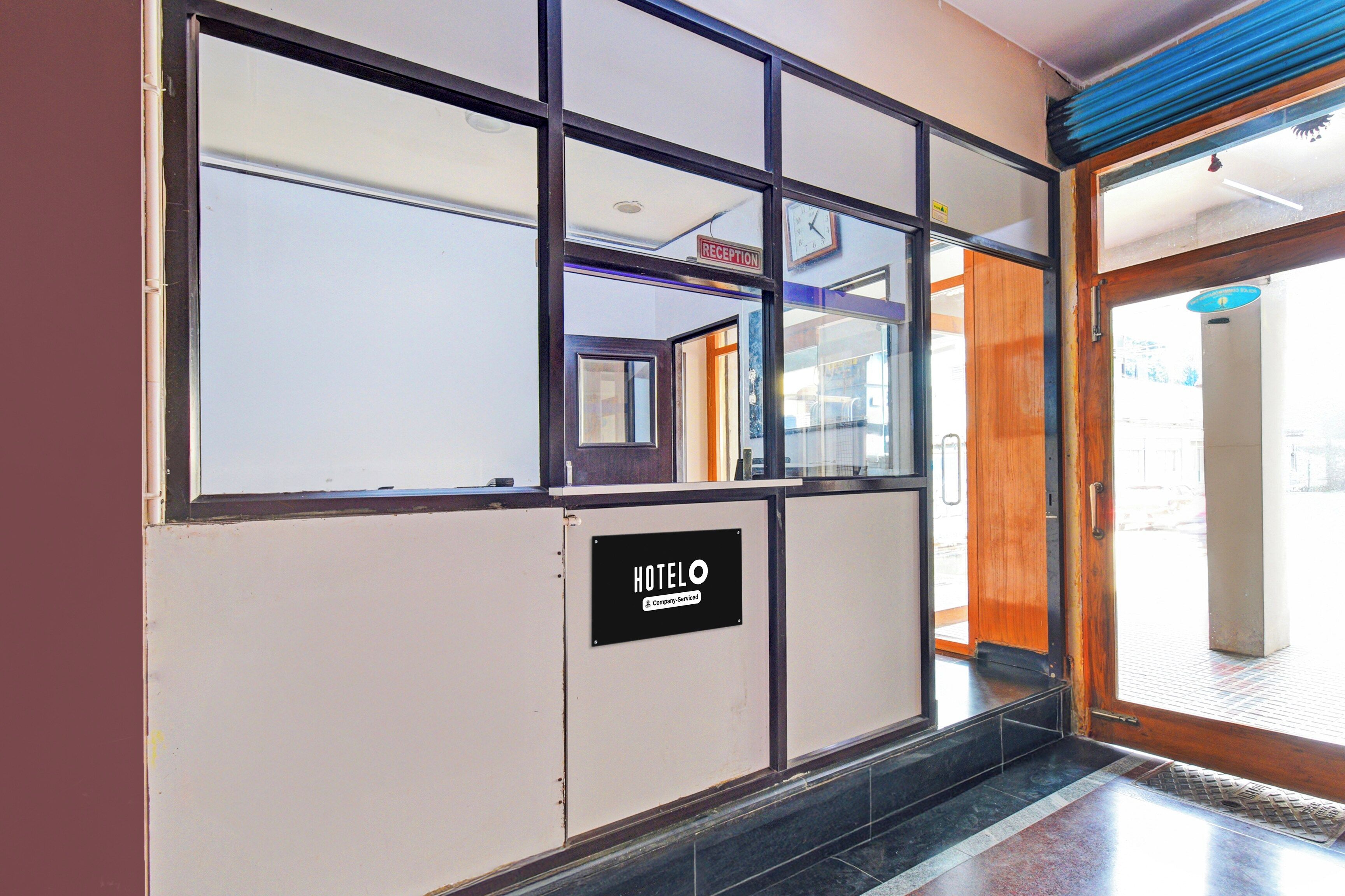 A reception area with a reception desk, a clock, and a sign indicating the hotel name.