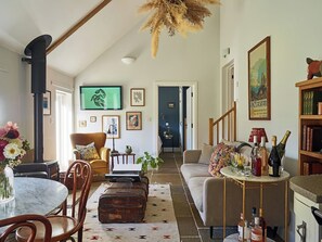A spacious living room with a high ceiling, a fireplace, a dining area with a round table, and a cozy seating arrangement. - The Renard - 19-23 Guests (Payhembury)
