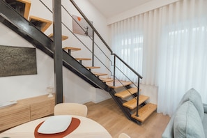 A modern interior with a staircase, wooden flooring, and a dining area with a table and chairs. - Modern Lapa Duplex D by Vacationy (Porto)