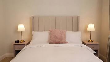 A neatly made bed with a headboard, two bedside tables with lamps, and a decorative pillow.