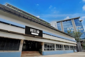 A hotel with a prominent 'HOTELO' sign, a company-serviced label, and a modern building with large windows in the background.