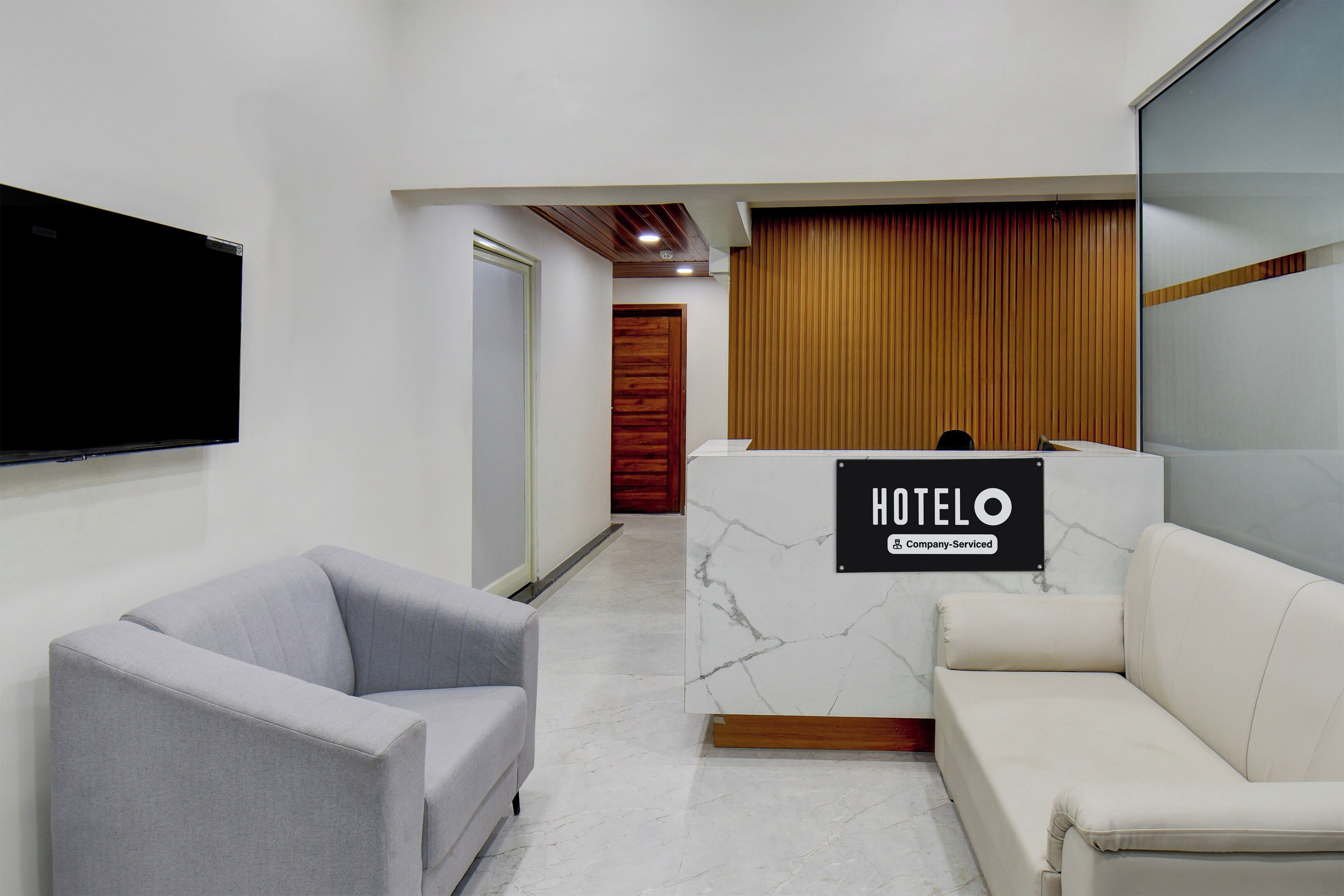 A hotel reception area with a marble reception desk, a grey armchair, and a white sofa.