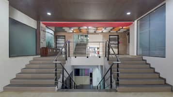 Ein modernes Interieur mit einer zentralen Treppe, einer roten Akzentwand und einer Decke mit runden Leuchten.