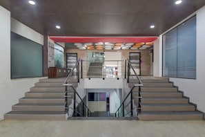 A modern interior with a central staircase, a red accent wall, and a ceiling with circular light fixtures. - Super Hotel O Pune Kasarwadi Railway (Pune)