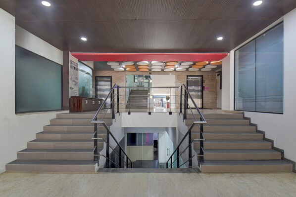 A modern interior with a central staircase, a red accent wall, and a ceiling with circular light fixtures.