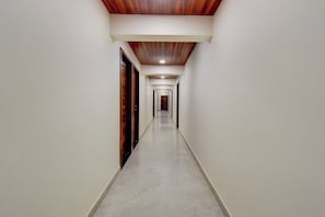 A corridor with wooden doors on one side and a marble floor. - Super Hotel O Pune Kasarwadi Railway (Pune)