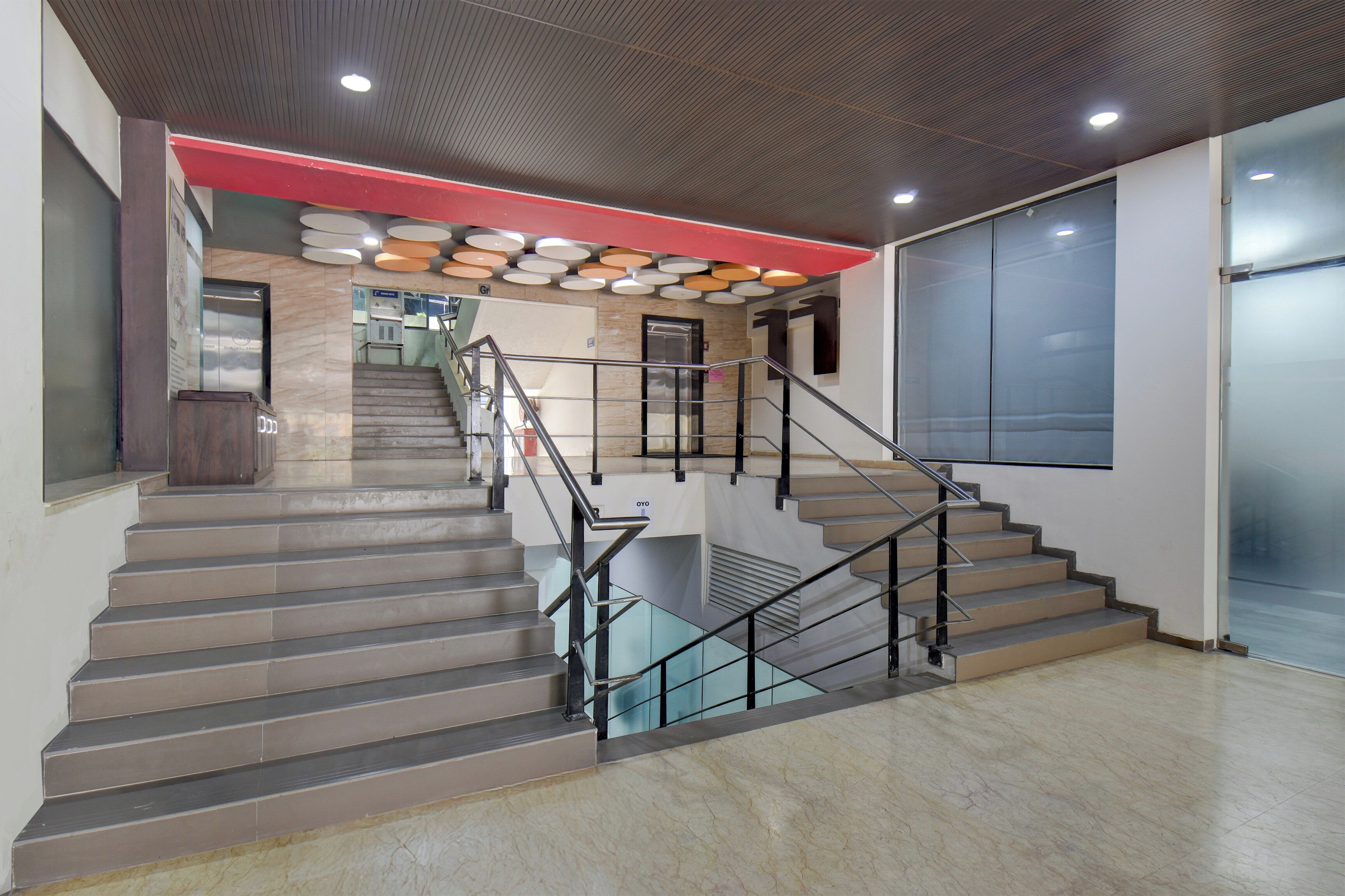 A staircase with glass railings and a red accent wall.