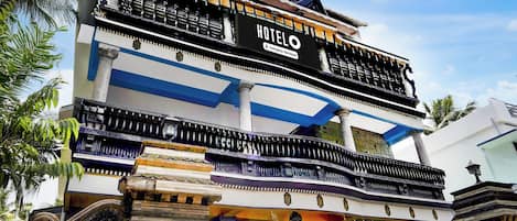 Un hotel con un cartel llamativo, varios balcones y elementos arquitectónicos tradicionales.