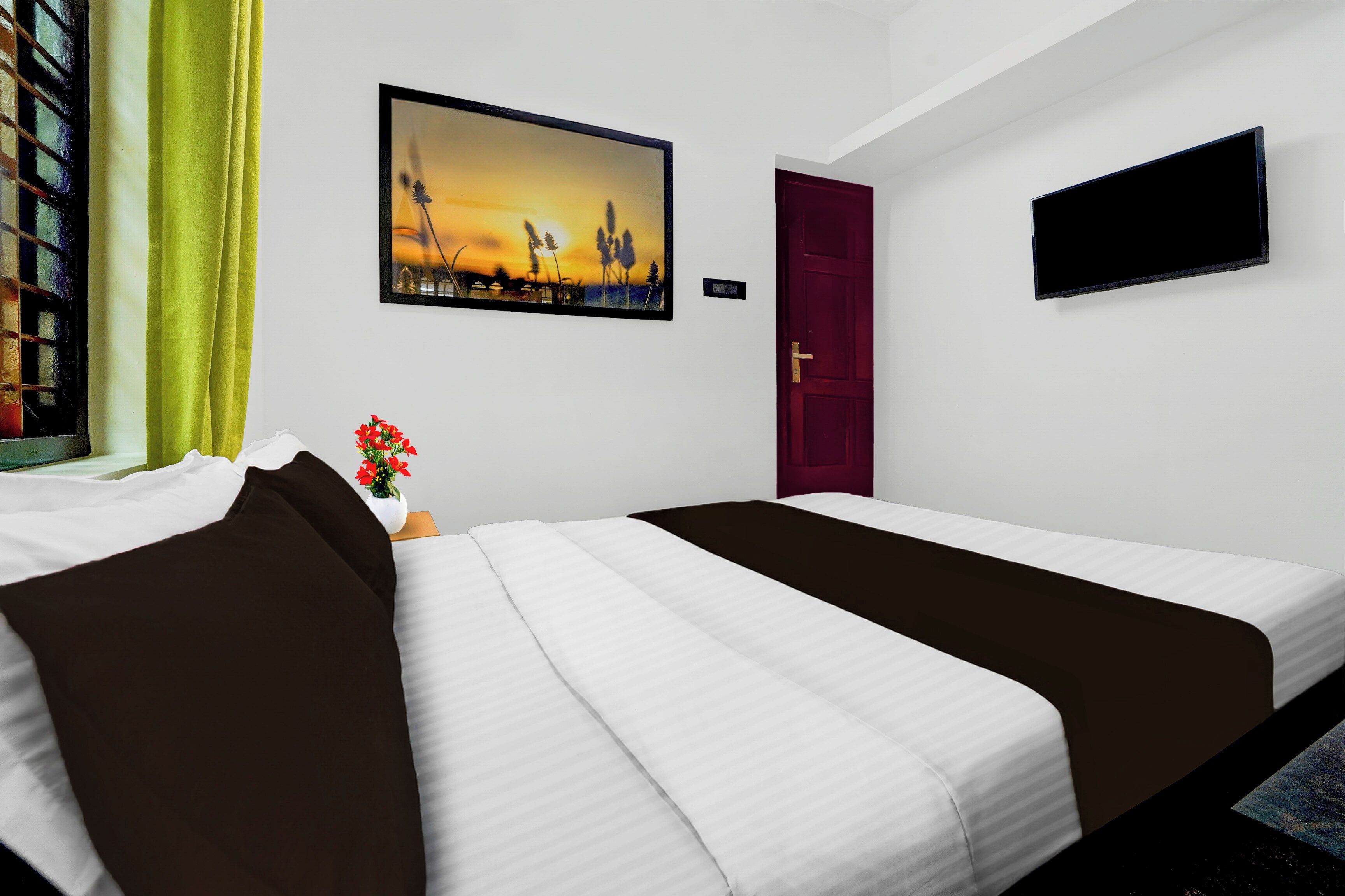 A hotel room with two beds, a painting of a sunset, a TV, and a window with curtains.