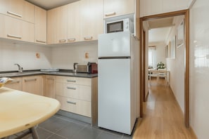 A modern kitchen with wooden cabinets, a built-in microwave, and a refrigerator. - Lusa Gaia S House by Vacationy (Vila Nova de Gaia)