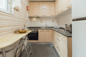 A compact kitchen with a built-in dishwasher, a sink, and a stove. - Lusa Gaia S House by Vacationy (Vila Nova de Gaia)