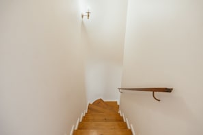 Eine enge Treppe mit Holzhinweisstufen und weißen Wänden.