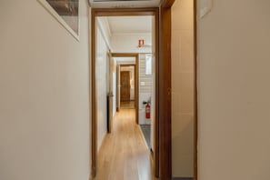 A hallway with a wooden floor, white walls, and a fire extinguisher mounted on the wall. - Lusa Gaia S House by Vacationy (Vila Nova de Gaia)