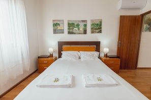 A hotel room with a bed, two bedside tables, a wooden headboard, and three paintings on the wall. - Lusa Gaia S House by Vacationy (Vila Nova de Gaia)