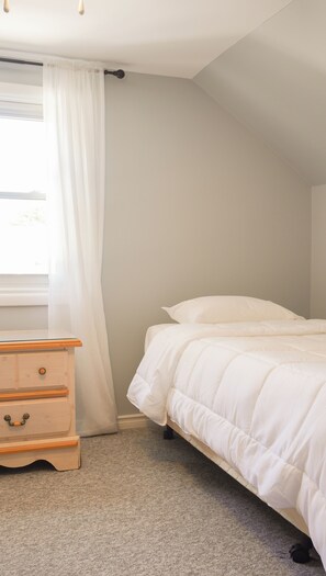 A bedroom with a bed, a dresser, and a window with curtains. - The Beach House - Deeded Beach Access (Brights Grove)