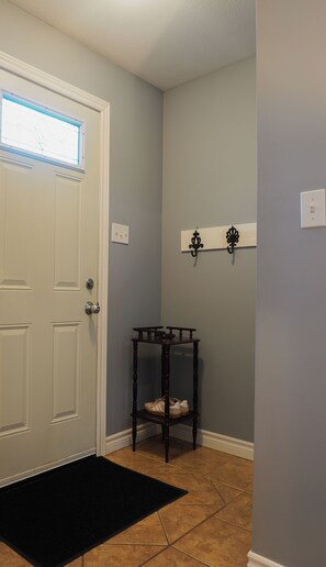 A hallway with a white door, a black bench, and a wall-mounted light fixture. - The Beach House - Deeded Beach Access (Brights Grove)