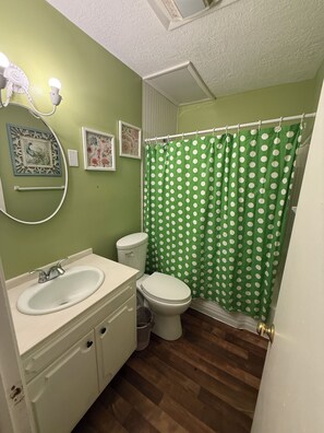 A bathroom with a green polka dot shower curtain, a white sink, and a toilet. - Row House Suite 927 (Topeka)