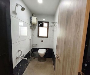 A compact bathroom with a toilet, a shower, and a sink. - Deluxe Room Tathawade (Wai)