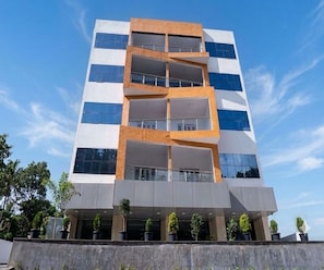 A multi-story building with a modern architectural design, featuring a combination of glass and brick facade, and a flat roof. - Deluxe Room Tathawade (Wai)