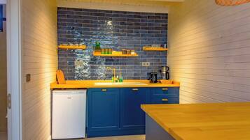 Eine kleine Küche mit blauen Schränken, einem weißen Geschirrspüler und einer Holz Arbeitsplatte.