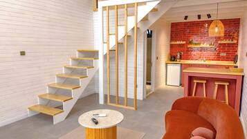A modern interior with a staircase, a kitchen area, and a seating area with a round table.